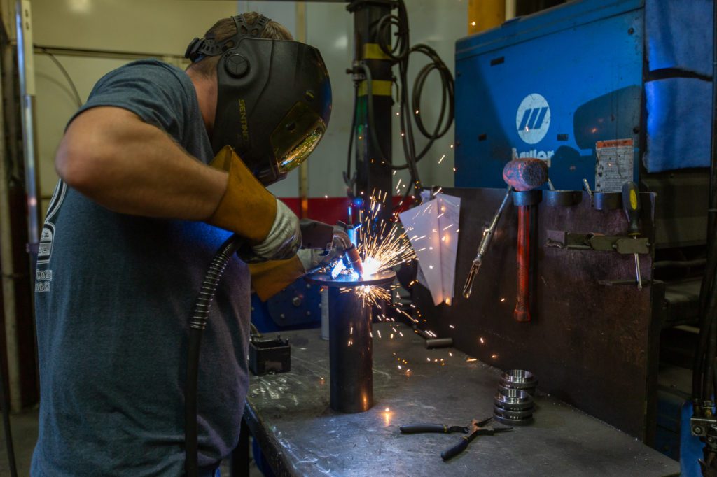 man wearing protective face shield completing an industrial strength weld