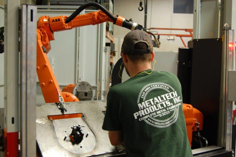 A Metaltech employee works on a robotic welding machine