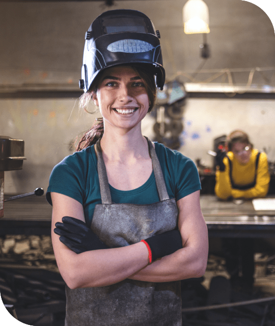 female welder crossing her arms and smiling at the camera