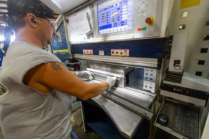 A machine operator uses a press brake to manipulate metal.