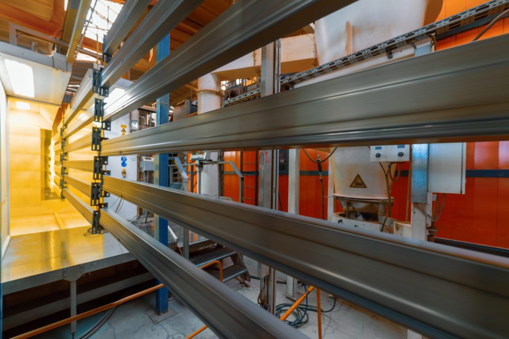 Metal going into a powder coating line and being coated yellow.