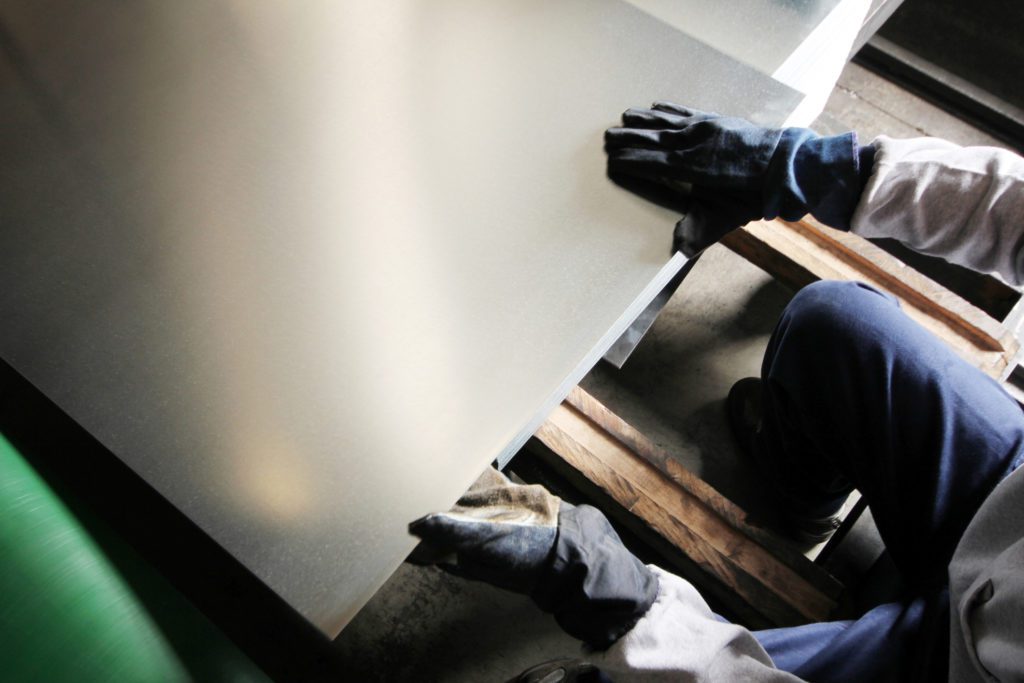 Person working with steel metal sheet.