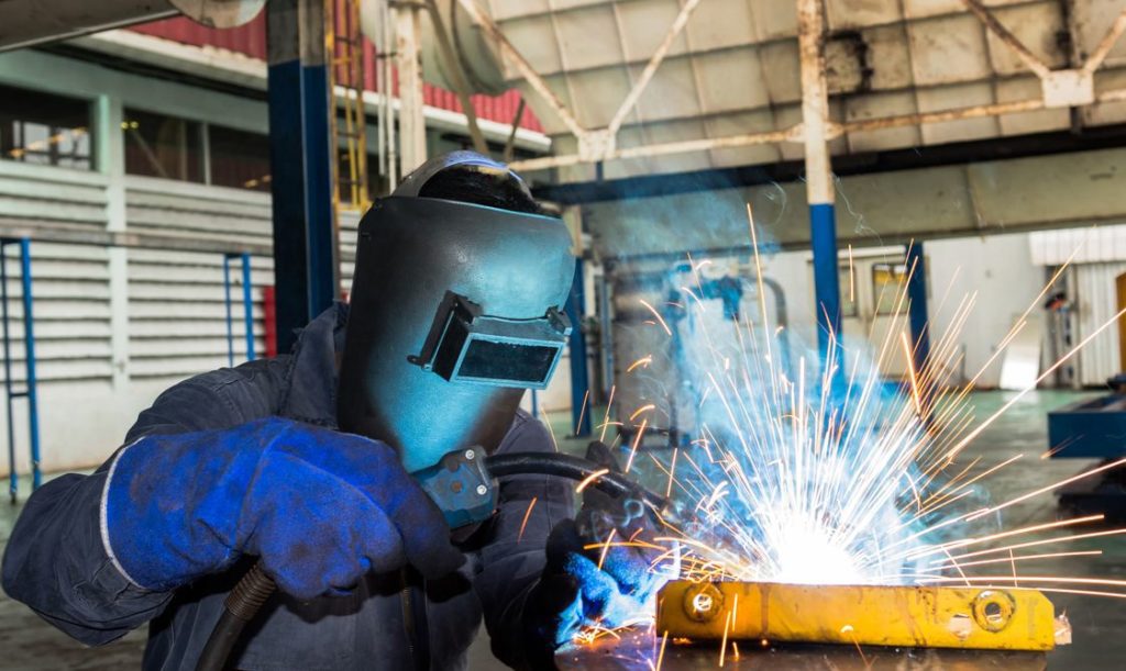 Welding professional performs MIG welding on a workpiece as sparks fly.