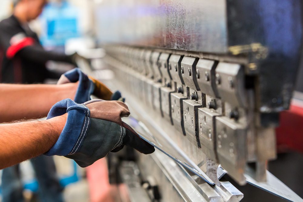 Employee bends sheet metal in a custom metal fabrication shop.