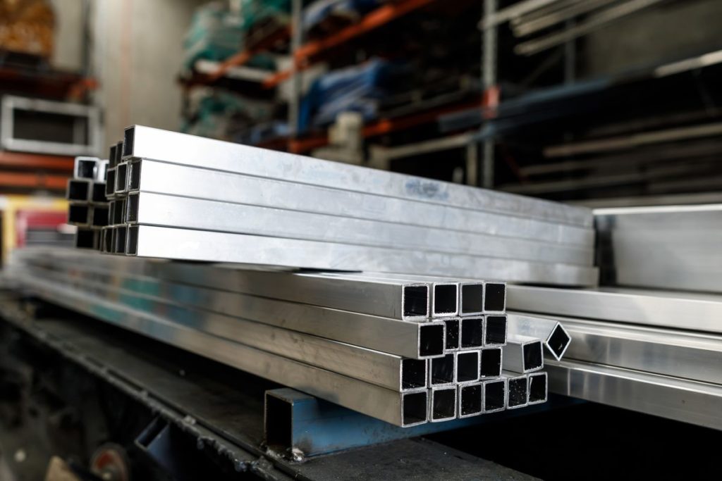 Stainless steel bars sit stacked in a custom metal fabrication shop.