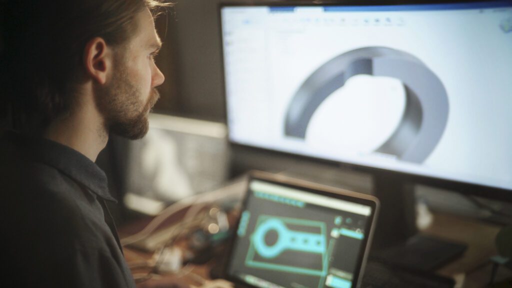 Design engineer working at his widescreen computer to make high quality and custom metal components.